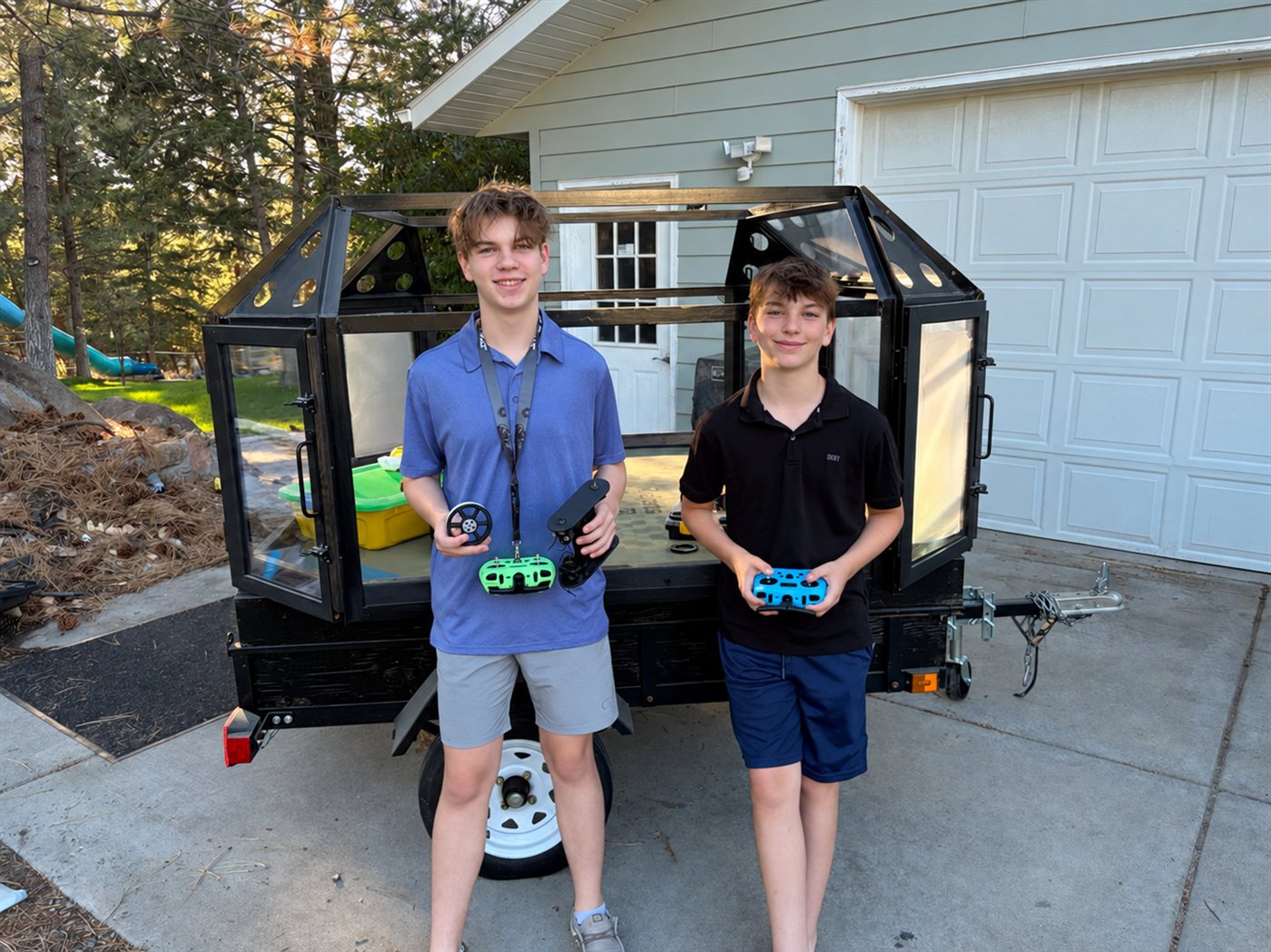 Cooper and Asher holding robot controllers beside the Riot Robots arena