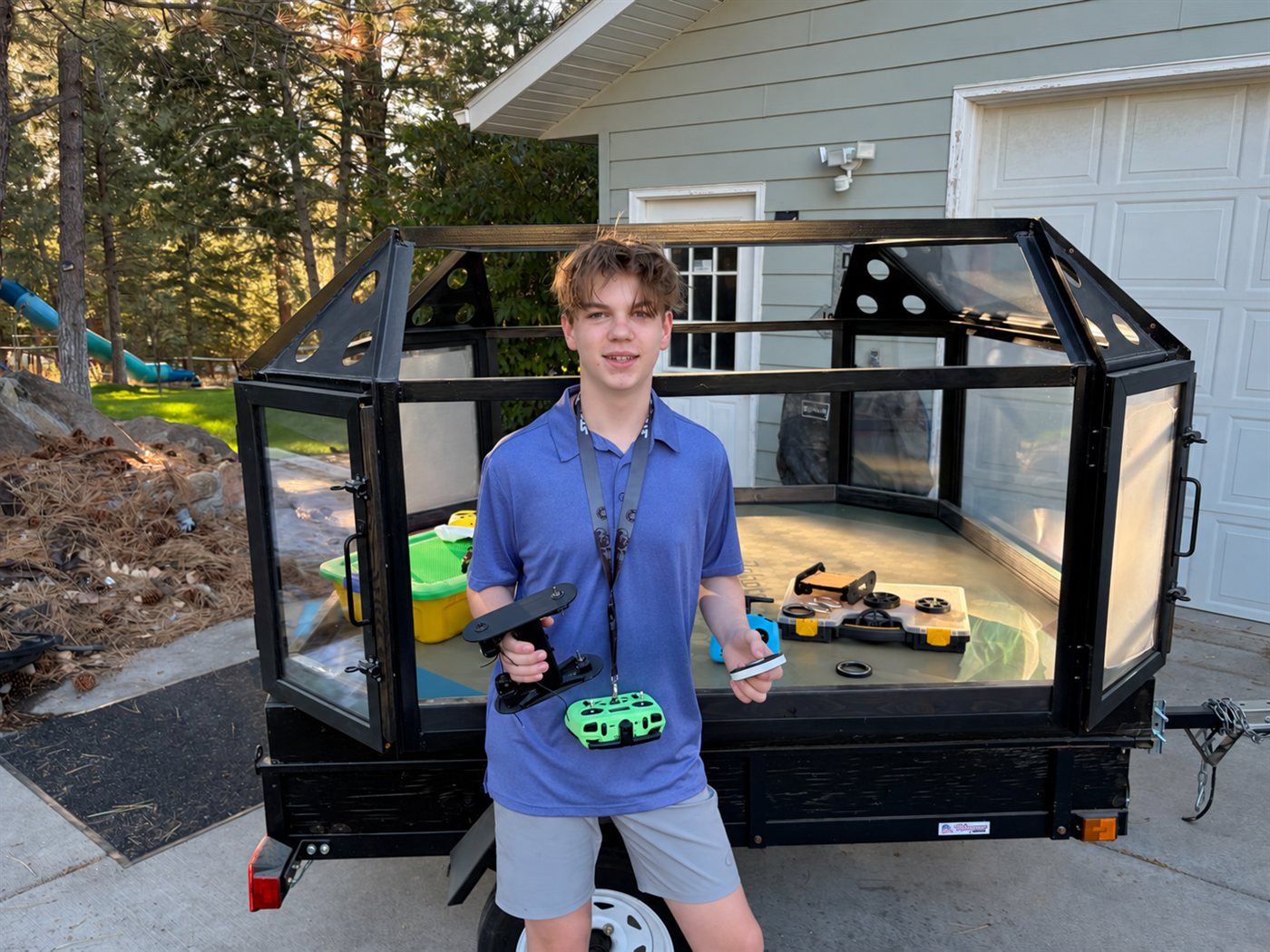 Cooper holding the robot v0.2 drive-base prototype beside the Riot Robots arena
